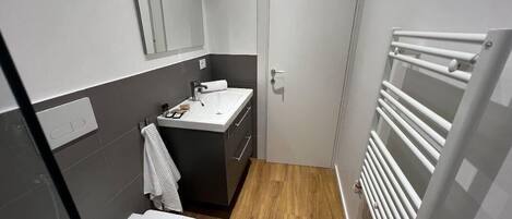 A compact bathroom with a toilet, sink, and mirror.