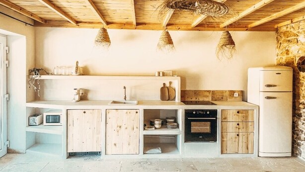 Une cuisine de taille réduite, dotée de meubles en bois, d’un réfrigérateur blanc et de luminaires suspendus.