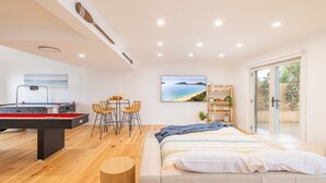 Une chambre moderne avec un lit, un bureau équipé d’une table de billard et un coin repas avec des chaises.