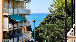 Un edificio de varios pisos con balcones que dan a un mar azul y despejado.