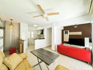 Un salon moderne avec un canapé rouge, une table basse en bois et un ventilateur de plafond.