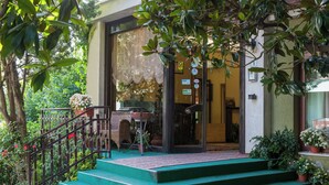 A building with a green staircase leading to a door with glass panels, surrounded by potted plants and a metal railing. - Hotel La Cantinella (Ostra)