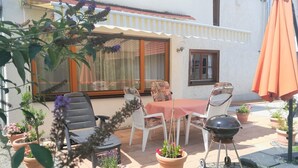 An outdoor patio with a table and chairs, potted plants, and a barbecue grill.