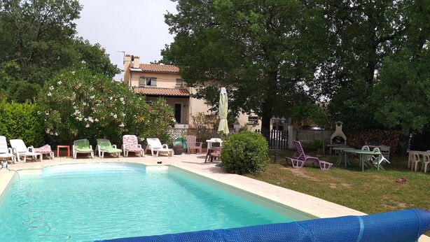 Une piscine avec des chaises longues et un espace barbecue.