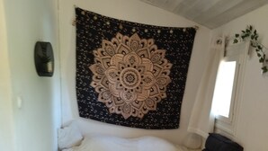 Un lit surmonté d’une grande et riche tapisserie, une couverture moelleuse posée sur le lit, et une petite table de chevet avec une lampe.