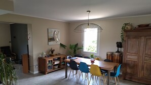 Un coin repas avec une table en bois, des chaises colorées, un buffet et une grande fenêtre laissant entrer la lumière naturelle.