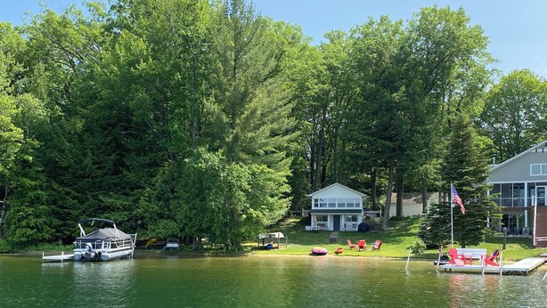 A lake with a dock and a house with a porch. - Idyllic 3-Bedroom Lake Front Cottage on Ford Lake (Fountain)