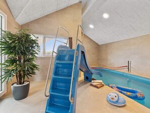 Ein Hallenbad mit blauer Rutsche, einer Topfpflanze und einem Schwimmdackel.