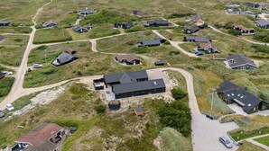 Een overzicht vanuit de lucht van een kustgebied met huizen, wegen en een strand.