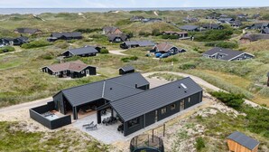 Een modern huis met een ruime patio, een zwembad en uitzicht op het omliggende landschap.