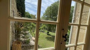 Blick durch ein Fenster auf eine steine Mauer und einen Rasen.