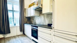Een moderne keuken met een inbouwoven, een rvs aanrecht en een raam met gordijnen.