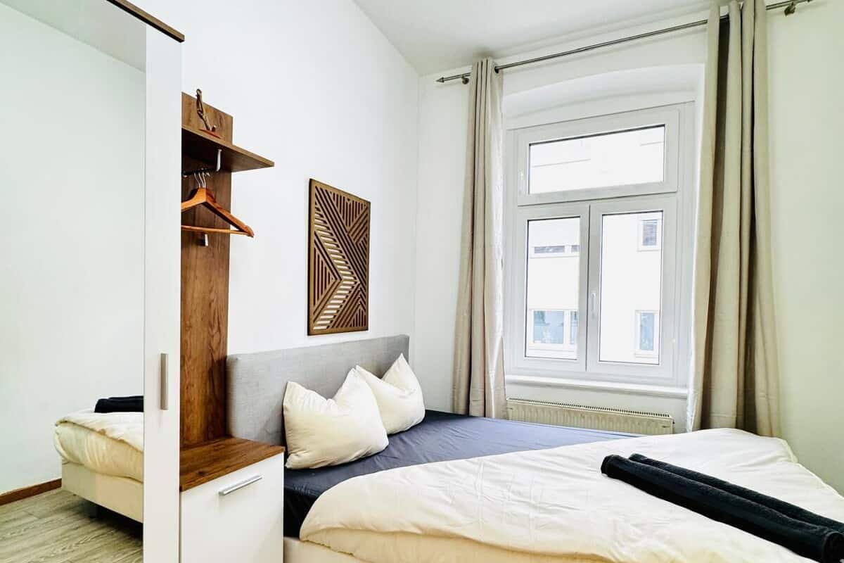 Un dormitorio moderno con cama, armario, espejo y ventana con cortinas.