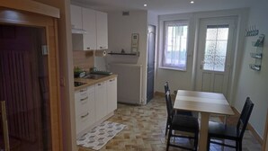 Une cuisine de taille réduite avec des meubles blancs, un plan de travail en bois et une table à manger avec des chaises.
