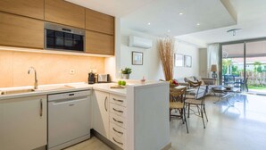 A modern kitchen with a dishwasher, a built-in oven, and a dining area with a table and chairs.