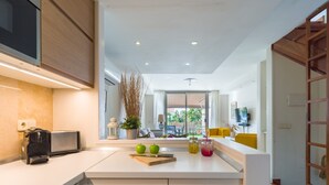 A modern kitchen with white cabinets, a built-in oven, and a large window overlooking a garden.