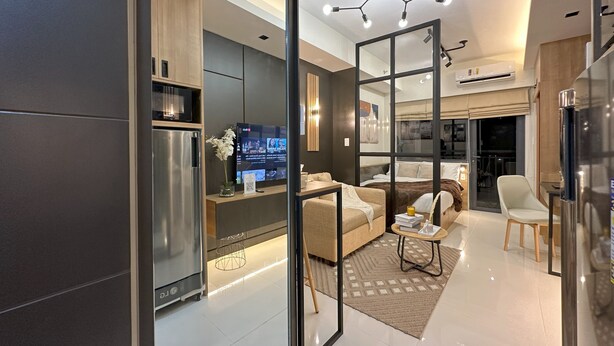 A modern living room with a sofa, coffee table, and a TV. There is a glass partition, a refrigerator, and a dining area visible. - Premium Suites City View, Makati CBD, Netflix, Wi-Fi & 20 mins to Airport (Makati)