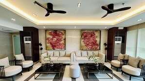 A modern living room with two sofas, a coffee table, and a ceiling fan. - Premium Suites City View, Makati CBD, Netflix, Wi-Fi & 20 mins to Airport (Makati)