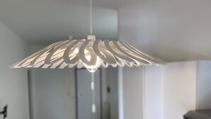 Una cocina moderna con armarios blancos, una silla amarilla y un lámpara colgante.