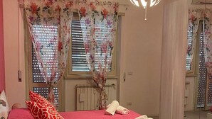 Un dormitorio con cama, almohadas, una mesita de noche, un espejo y una lámpara colgante.
