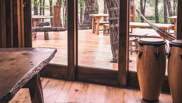 An interior view of a wooden-floored room with a large window overlooking an outdoor deck area.