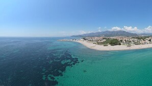 An aerial view of a coastal town with a beach, clear turquoise waters, and a mountainous backdrop. - Poolvilla Michelle near the beach (Mont-roig del Camp)