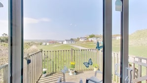 A view from a balcony with a wooden railing, potted plants, and a butterfly decoration. - D48 Sunvale, Riviere Towans (Hayle)