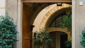 An arched entrance with a wooden door, potted plants, and a stone pathway leading to an interior courtyard. - Casa Santa Sofia con Terrazza by Wonderful Italy (Palermo)