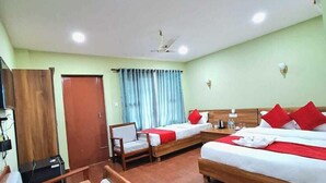 Ein Hotelzimmer mit einem hölzernen Bett, einem Schreibtisch aus Holz, einem Stuhl, einem Telefon und einem Fenster mit Vorhängen.