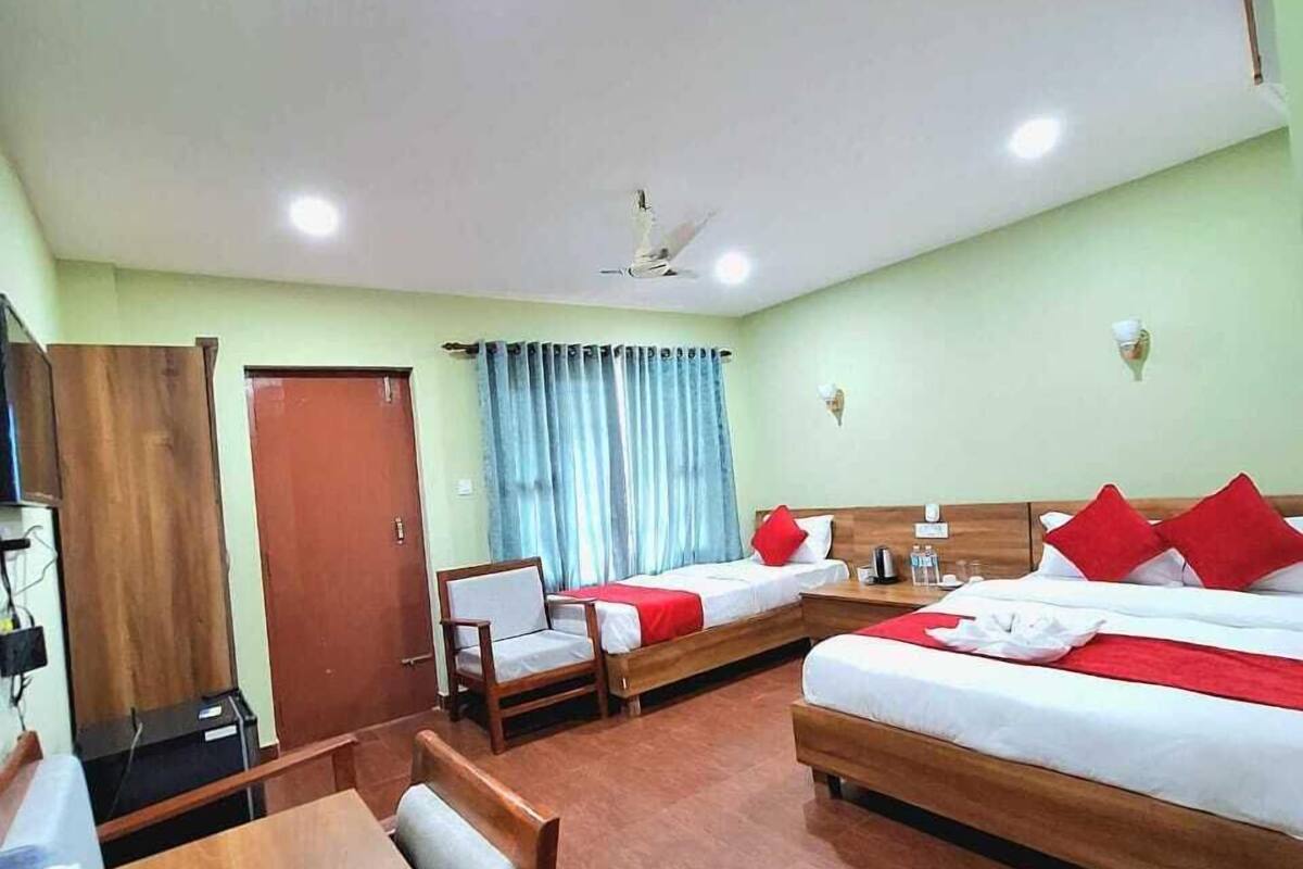 A hotel room with a wooden bed, a wooden desk, a chair, a telephone, and a window with curtains.