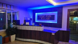 Ein Empfangsschalter mit einer digitalen Anzeige, auf der 'SIGAI PARK VILLAGE' steht, und einem 'VISA'-Schild.
