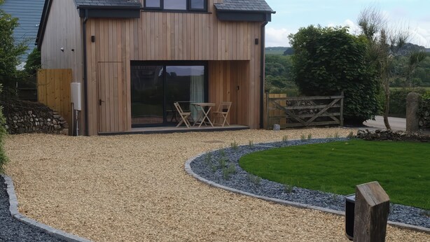 A wooden house with a sloped roof, a large sliding glass door, and a small patio with outdoor furniture.