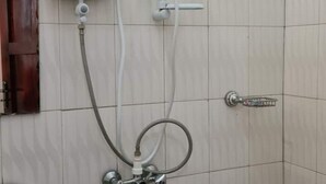A bathroom with a shower, toilet, and a towel rack. - BLT Guest House, Kasese (Kasese)