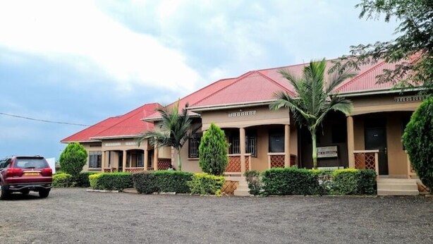 A hotel with a red roof, multiple rooms, and a gravel driveway. - BLT Guest House, Kasese (Kasese)