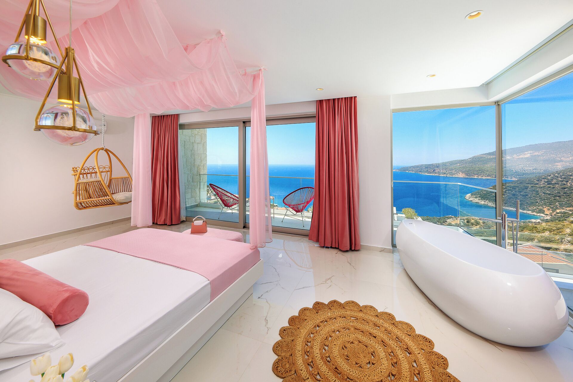 Un dormitorio moderno con una cama grande, una zona de estar con una silla, una bañera y vistas al mar.