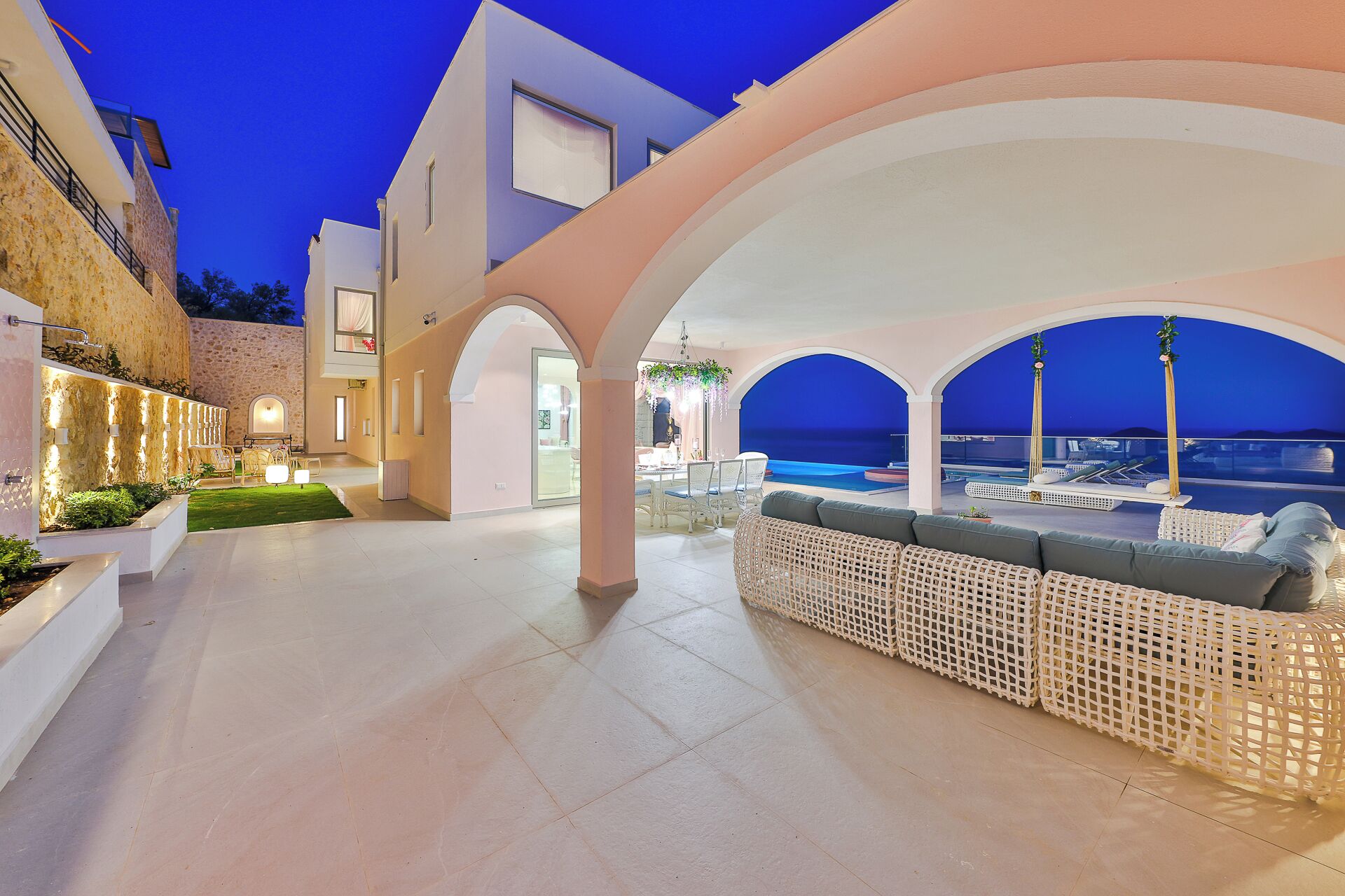 A modern outdoor area with a pool, seating, and a view of the sea.