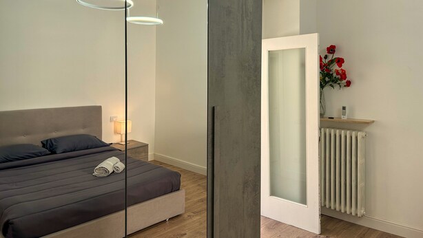 Un dormitorio moderno con cama, lámpara de noche y radiador.
