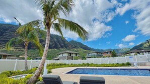 A pool area with lounge chairs, a palm tree, and a view of mountains. - @ Marbella Lane - Serene & Lovely MT + Ocean Views (Waianae)
