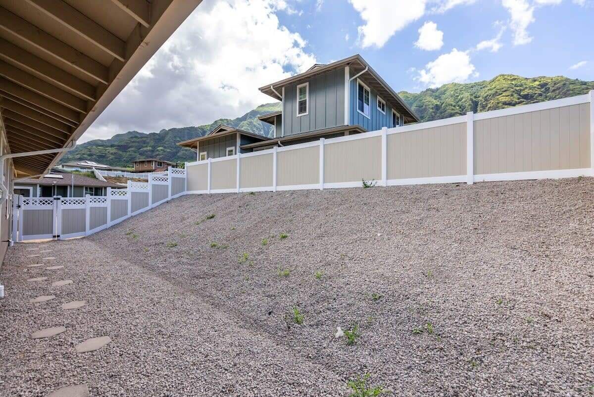 Un barrio residencial con camino de grava, cerca blanca y casas con techos inclinados.