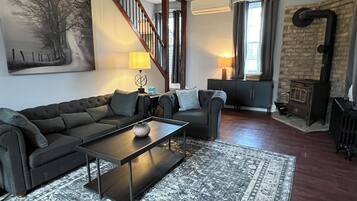 A living room with a sofa, a coffee table, a rug, a fireplace, and a staircase.
