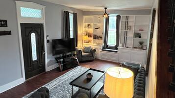 A living room with a TV, sofa, coffee table, and lamp.