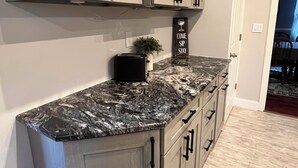 A kitchen with light gray cabinets, a black marble countertop, and a small potted plant. - The Vintage on Market, w/Pool, near Hershey, Ironstone Ranch & Spooky Nook (Elizabethtown)