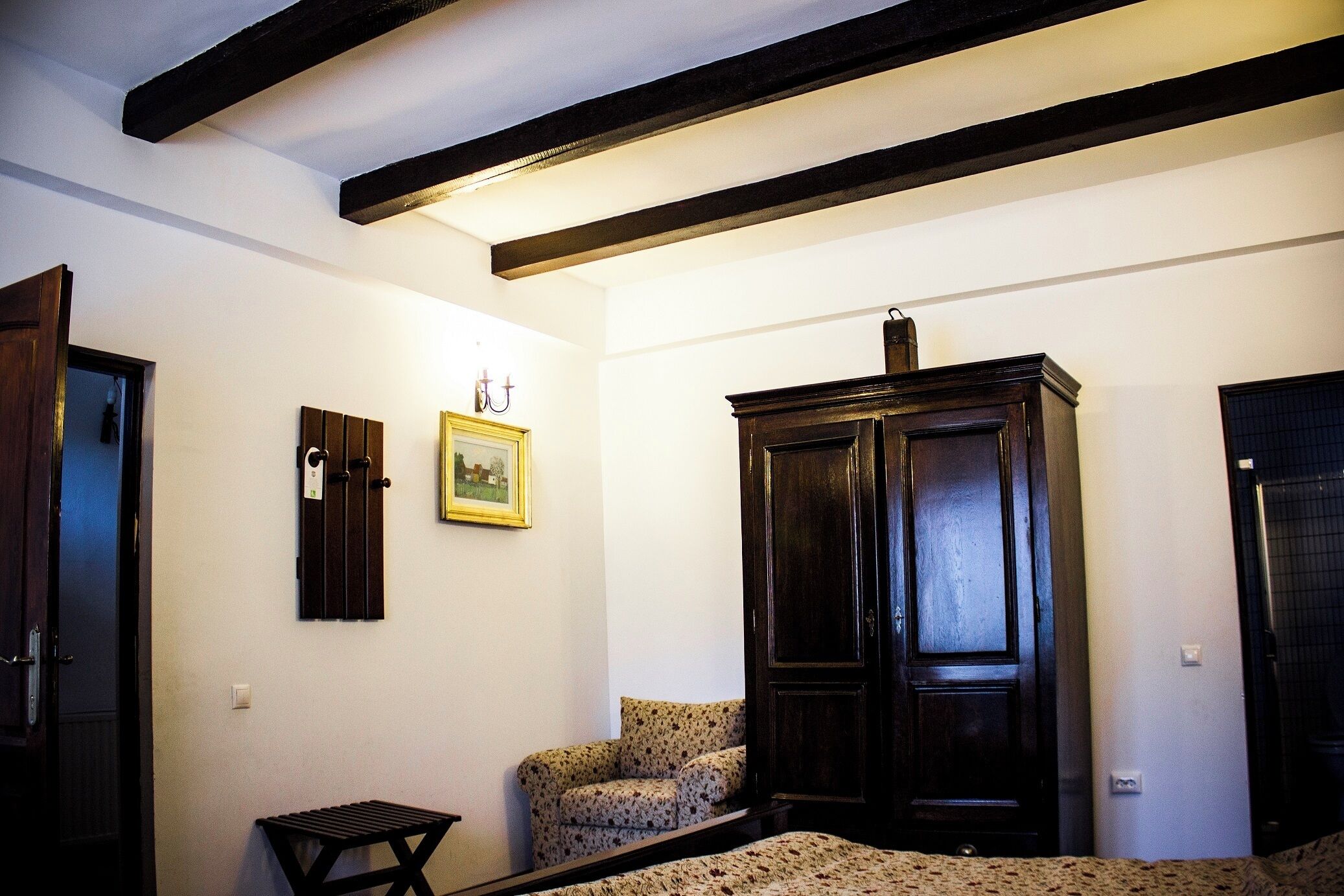 Una habitación con una cama, un armario de madera, una mesita y una silla.