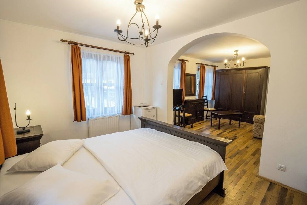 A hotel room with a large bed, a desk, a chair, and a wardrobe.