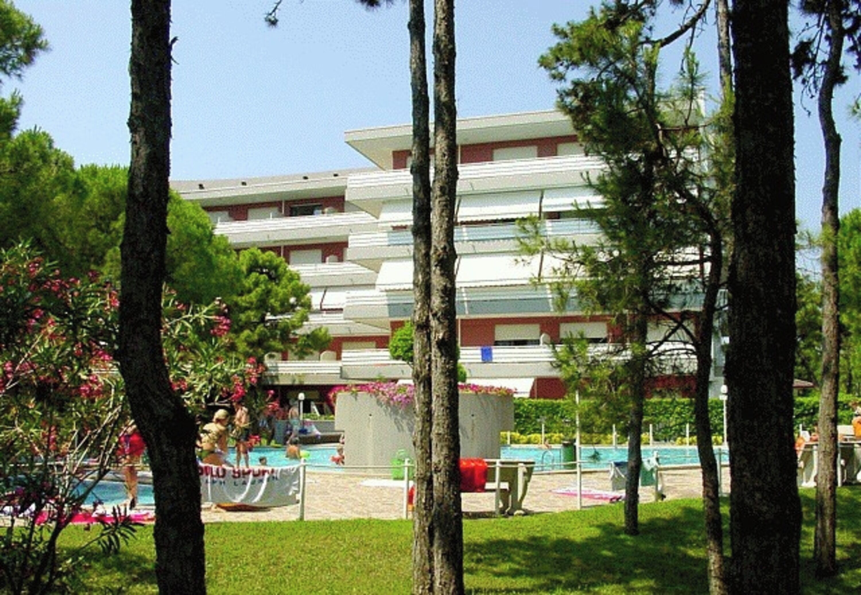 Un hotel de varios pisos con una zona de piscina rodeada de árboles.