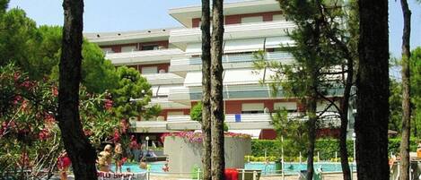 A multi-story hotel with a pool area surrounded by trees.