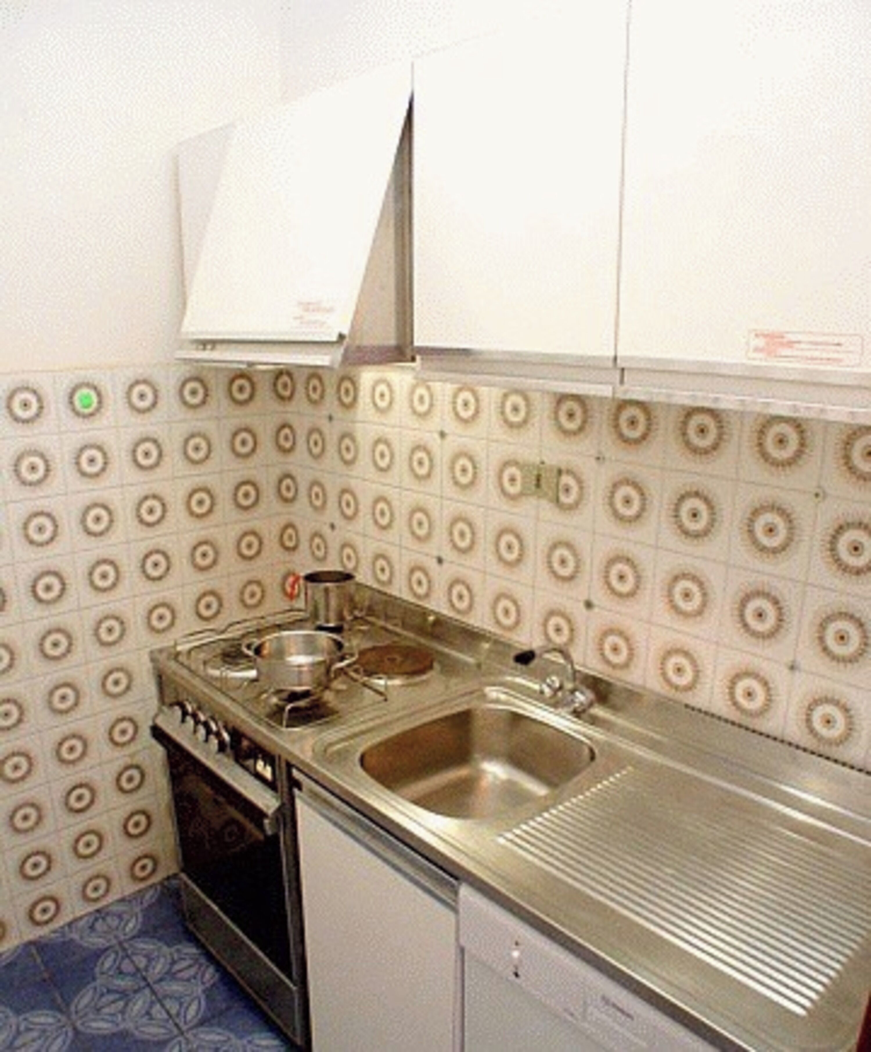 A compact kitchen with a stove, sink, and a small refrigerator.