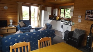 Interior acogedor de una cabaña con sala de estar, comedor y cocina.