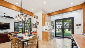 Una cocina moderna con armarios de madera, un comedor con mesa y sillas, y un ventanal con vistas al exterior.
