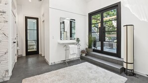 Un baño moderno con un ventanal grande, un lavabo blanco y un espejo.